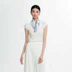 Model in white knitwear with the pale blue botanical silk scarf folded narrow at the neck