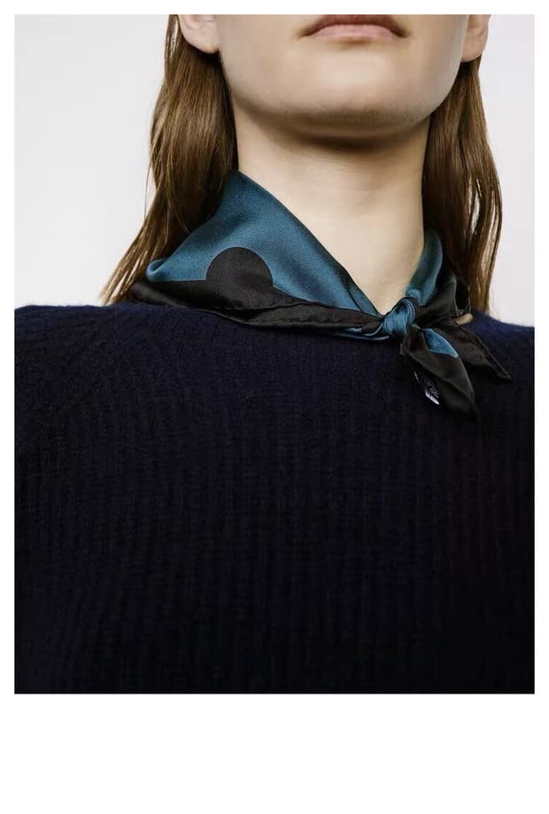Model in a navy knit sweater with the steel blue dotted silk square tied close at the neck