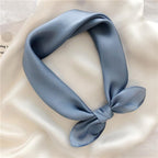 Dusty blue silk square knotted and laid on ivory silk, glossy charmeuse face turned up