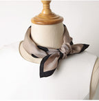 Greige dotted silk square tied at the neck of a cream linen dress form with a wooden stand
