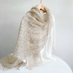 Polka dot linen scarf draped, the beige flax ground reading through between the printed dots