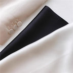 Ivory silk next to a folded black silk corner, three fabric covered buttons alongside