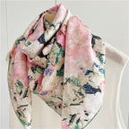 The painterly floral silk scarf draped over a cream knit