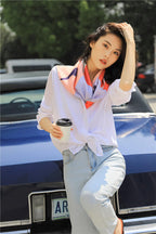 Model leaning on a car wearing the coral and lilac fashion figure silk scarf over a white shirt