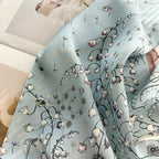 Soft folds of misty blue silk printed with dandelion clocks and lily-of-the-valley stems