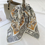 Cream animal-print square knotted onto the handle of a beige handbag