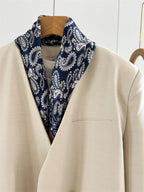 Navy paisley square folded into a wide shawl collar over a cream jacket