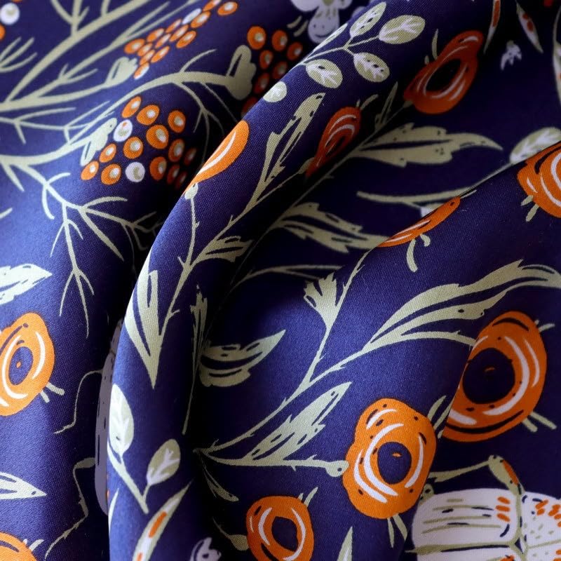 Close-up of navy silk folds printed with orange blooms and slender sage leaves