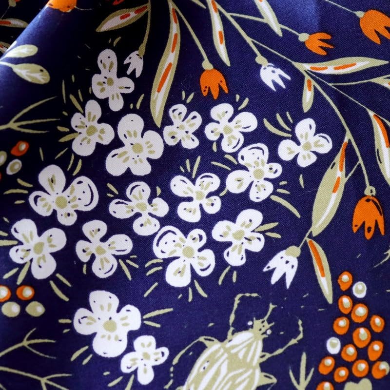 Macro of white blossom clusters, orange buds and a small beetle on navy charmeuse