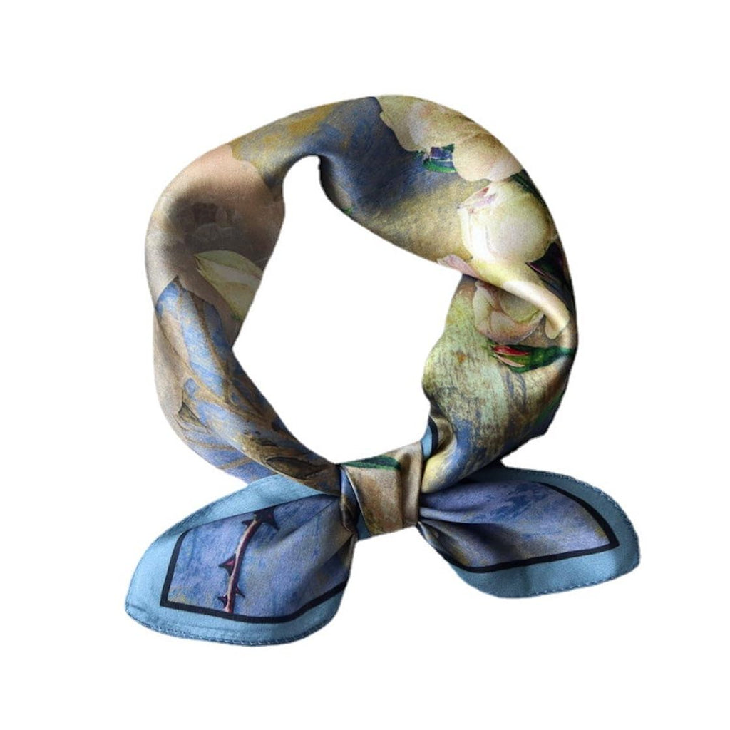Blue camellia-print square twisted into a loop and knotted, blue bordered tails below