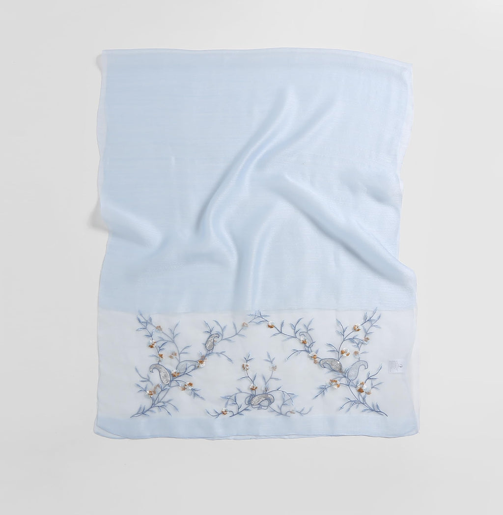 Pale blue shawl folded flat showing full width with the vine band along the bottom edge