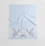 Pale blue shawl folded flat showing full width with the vine band along the bottom edge