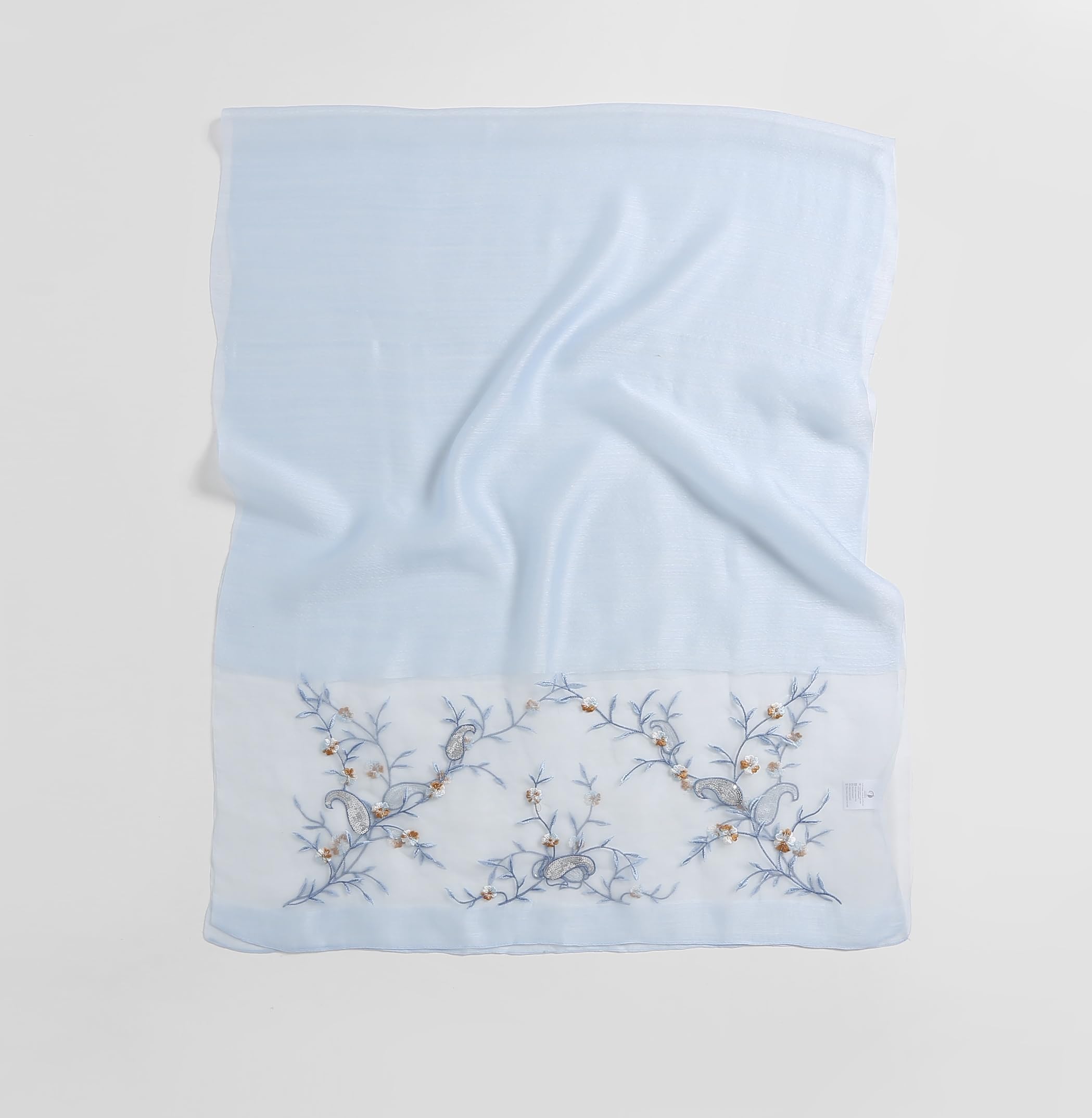 Pale blue shawl folded flat showing full width with the vine band along the bottom edge