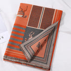Folded shawl on white cloth showing the orange stripe bands and a horse panel with the grey reverse peeking out