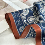 The rust border band rolling over a fold with navy paisley on either side