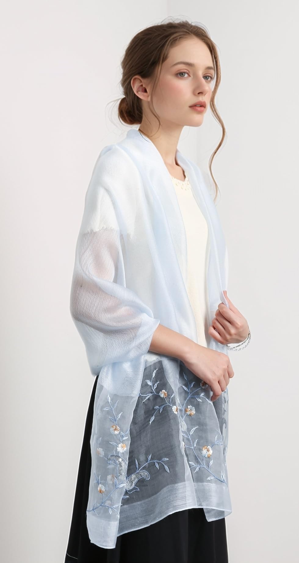 Model wearing the pale blue shawl open over a cream top and black skirt