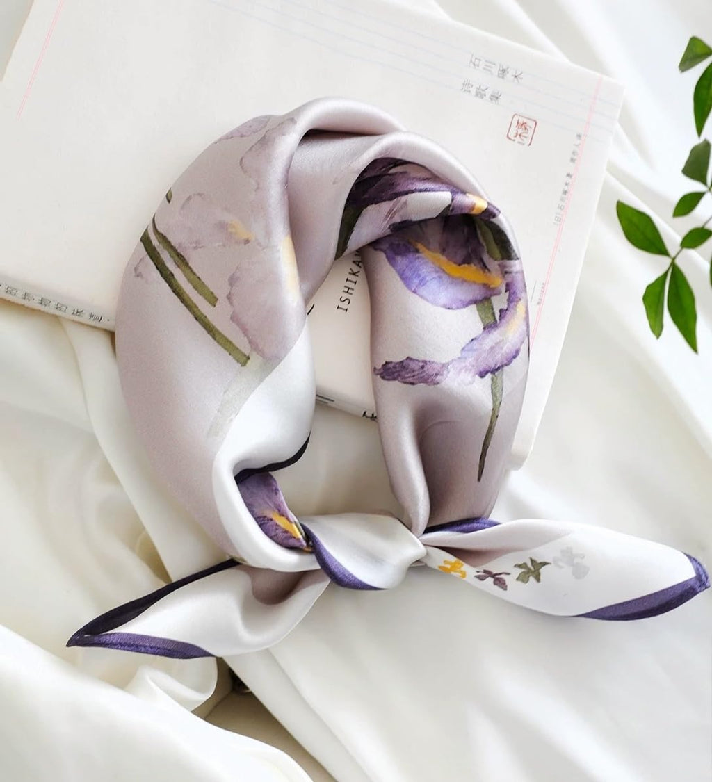 Mauve iris square coiled and knotted beside an open book and green leaves