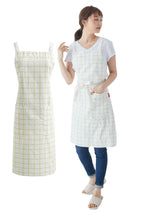 Woman in a pale green windowpane check cross back apron next to the same apron flat
