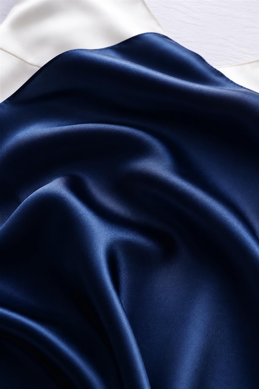 Navy silk charmeuse falling in deep folds against a cream backdrop