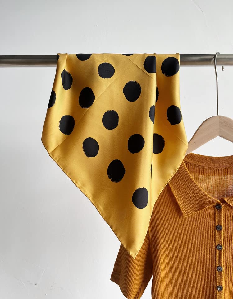 Golden yellow silk square with brushed black dots hung on a rail beside a mustard shirt