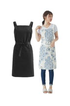 Plain black apron beside a woman wearing the blue floral print cross back apron