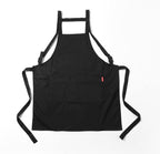 Black cotton apron laid flat showing the H shaped back straps and the long waist ties