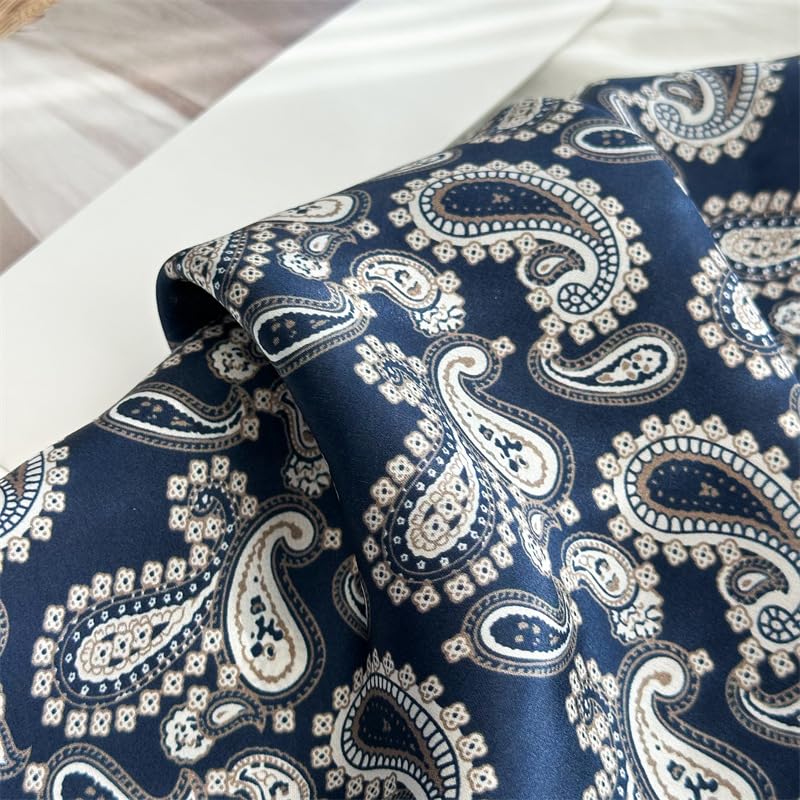 Close-up of navy charmeuse folds, cream paisley motifs catching the light