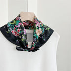 Black bouquet square tied at the neck of a white knit top on a dress form