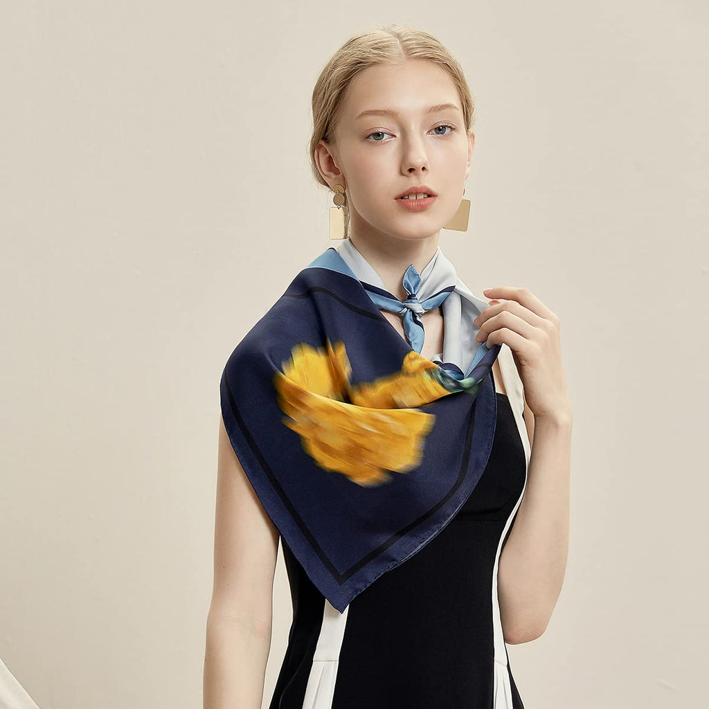 Model in a navy dress wearing the colour block silk scarf with the yellow bloom at the shoulder
