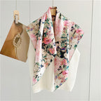 The blush and teal painted floral silk scarf hanging open on a wooden hanger