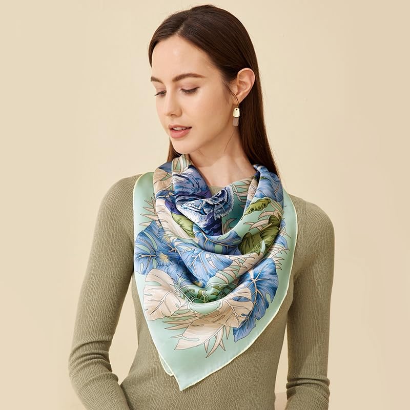 Blue and green tropical print silk scarf folded into a triangle at the neck