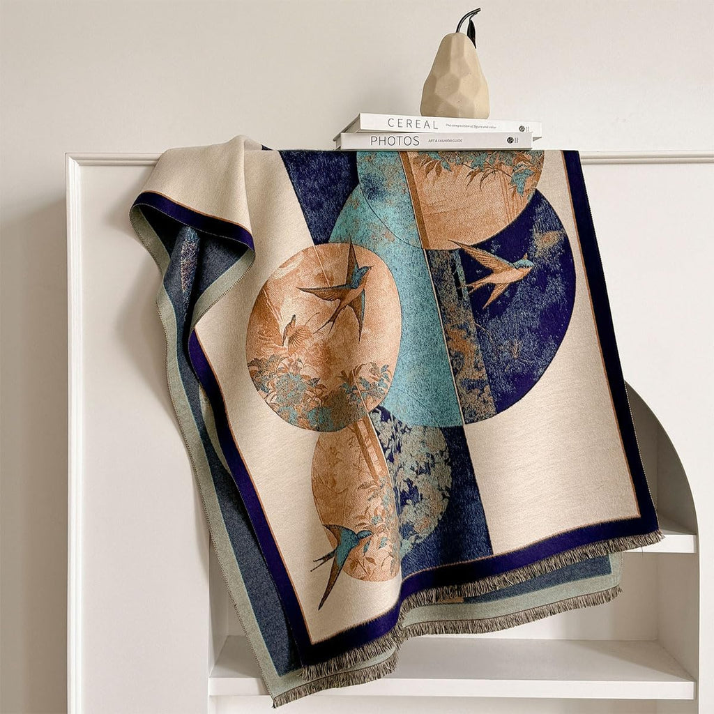 Swallow and fan shawl laid over a white shelf edge showing the ochre fan disc and the navy border
