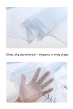 Fabric close up and a hand behind the sheer pale blue ground