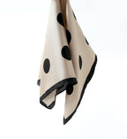 Greige silk square with black dots hanging in soft folds, black border down the edges