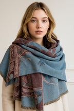 Woman wearing the blue Eiffel Tower shawl looped high at the neck over a cream coat