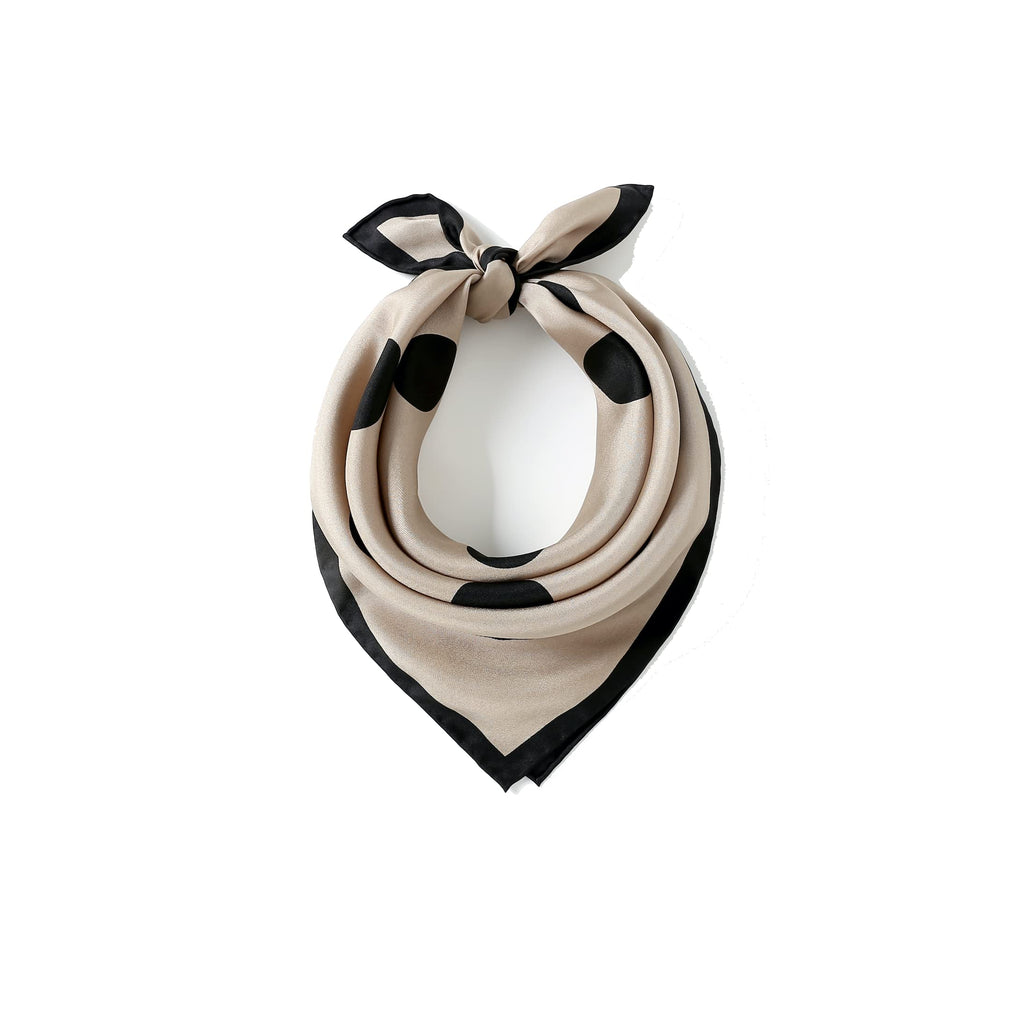 Greige silk square with black dots coiled at a white bust, bow tied at the top