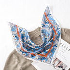 Blue silk square printed with cream blooms and a burnt orange band, draped over a beige knit