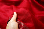 Hand lifting the sheer beaded panel away from the solid red body