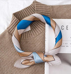 Cat print square rolled into a loop on a camel sweater, fine striped border on show