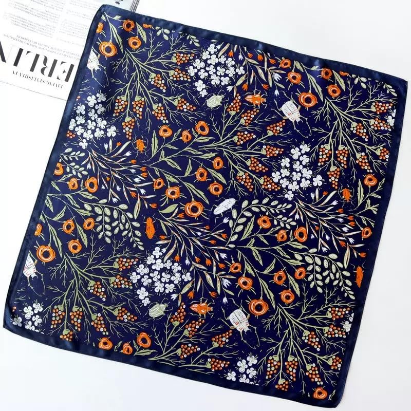 Navy square laid flat, orange blooms and white blossom over sage leaves and berries
