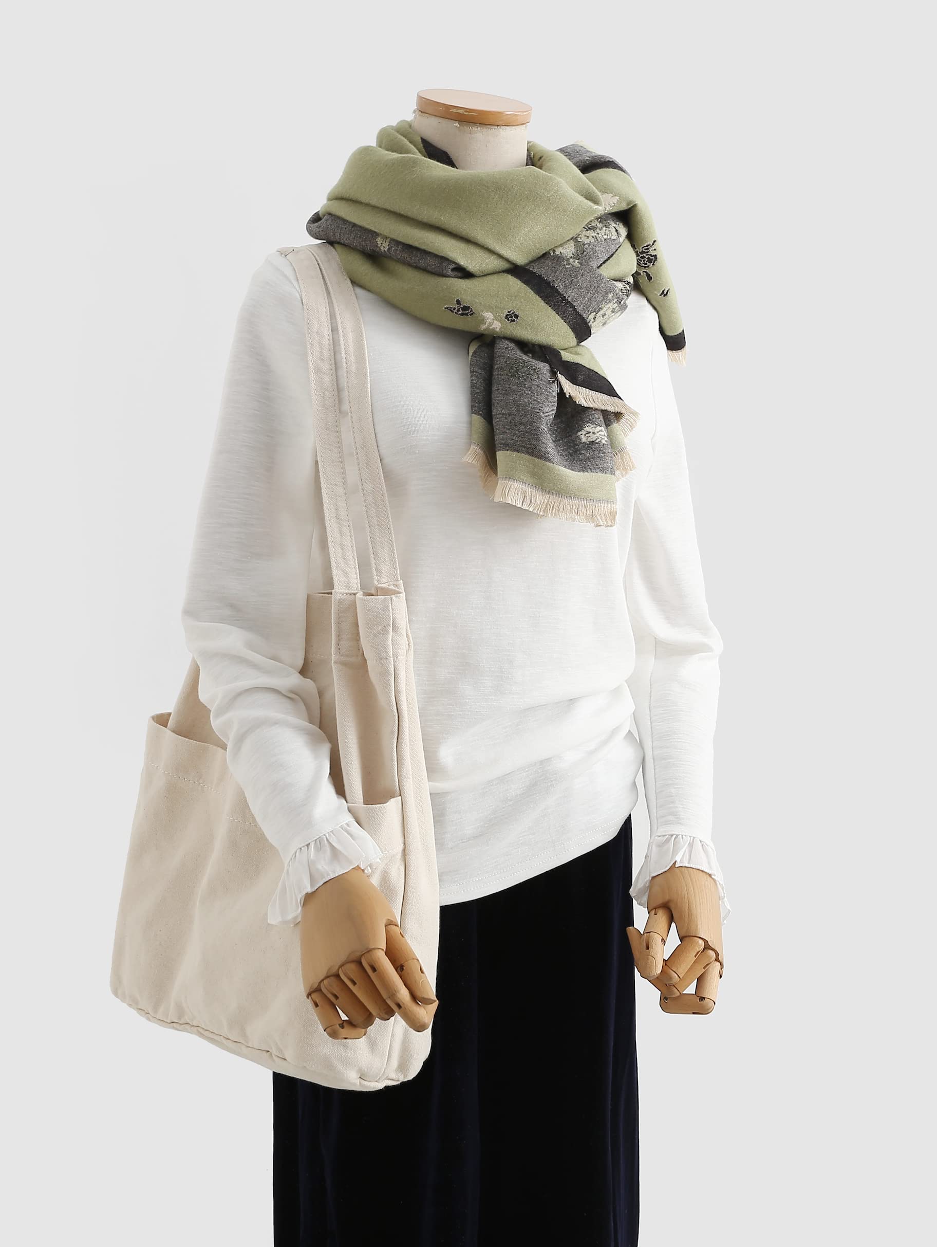 Mannequin in a white top wearing the sage shawl looped high at the neck with a canvas tote on the shoulder