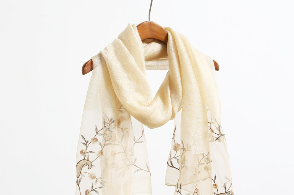 Khaki shawl on a wooden hanger showing the embroidered end panels