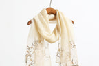 Khaki shawl on a wooden hanger showing the embroidered end panels