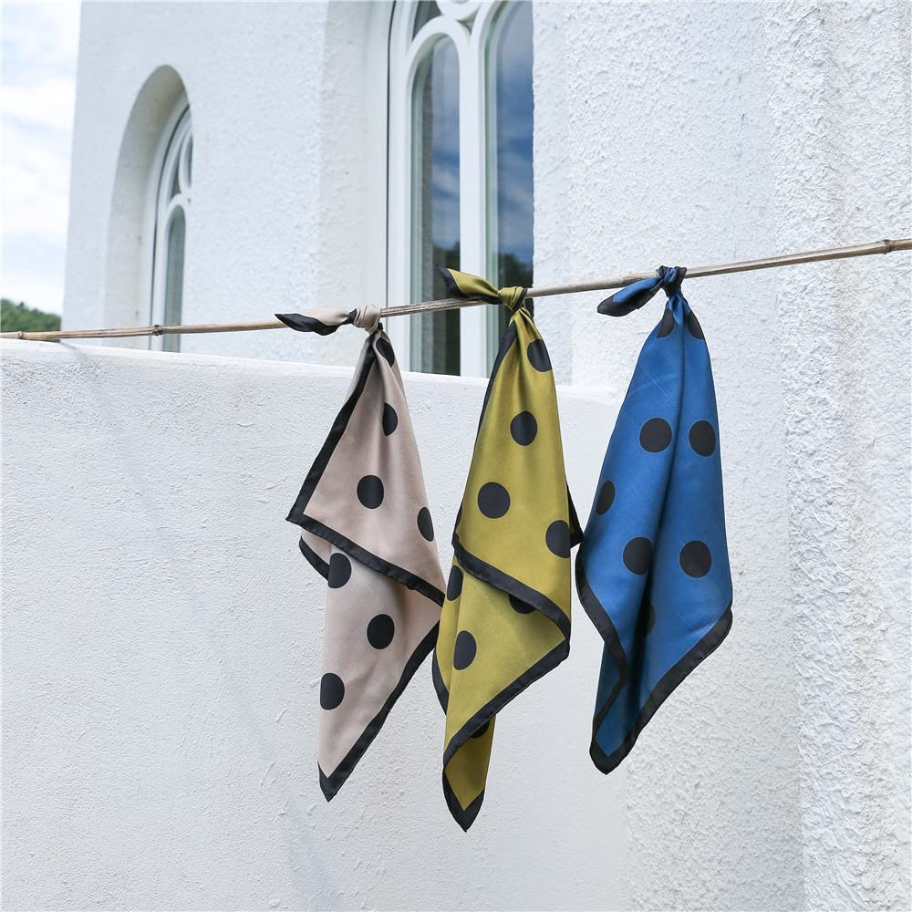 Greige, olive and steel blue dotted silk squares knotted on a bamboo pole by a white wall