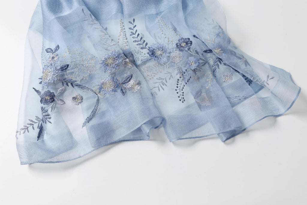 Angled view of the embroidered end panel showing the sheer border and pattern placement