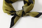 Close-up of the knot: olive silk twill sheen and the black border running along the tails