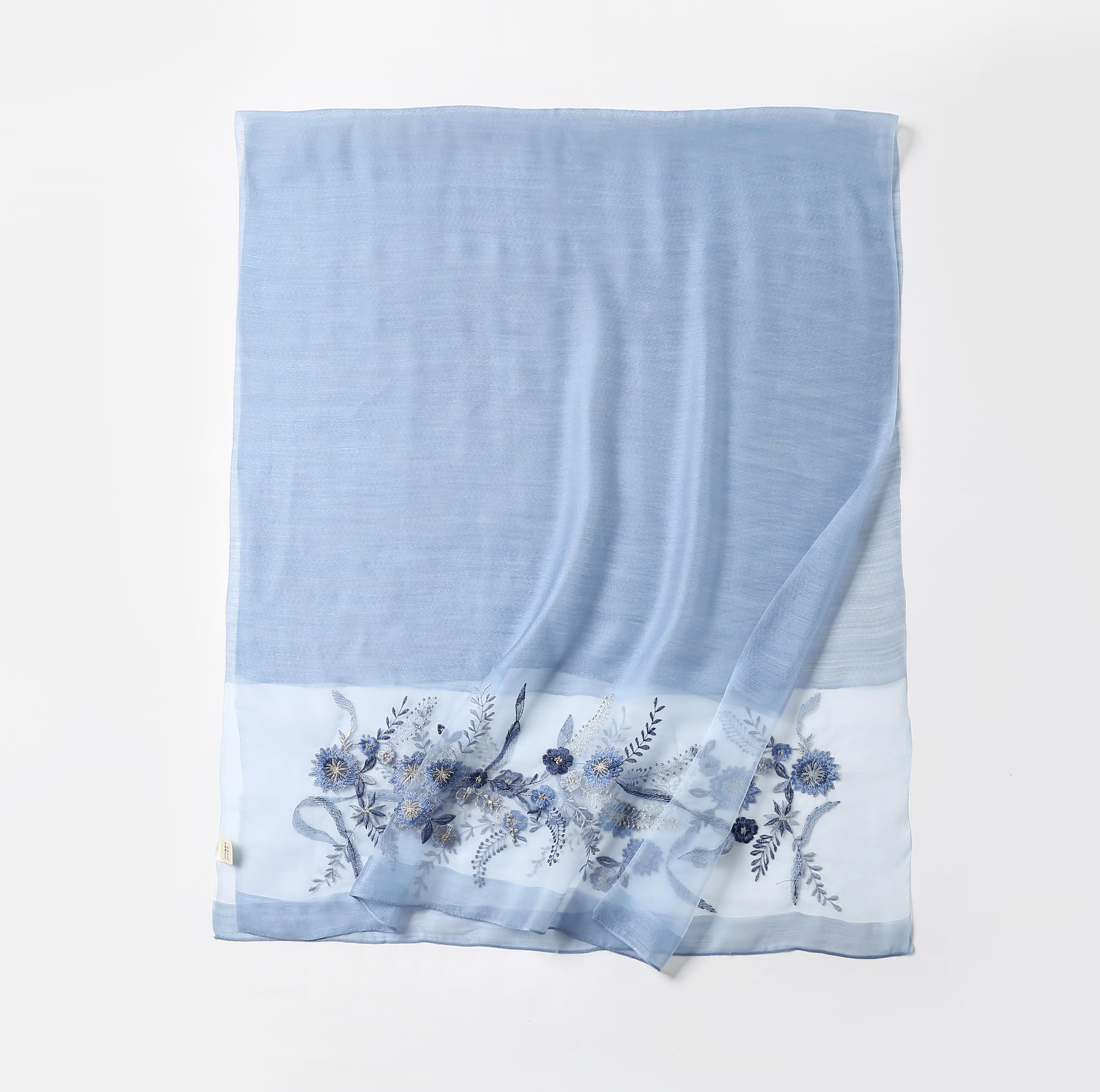 Denim blue shawl folded flat showing full width with the embroidered band along the bottom edge