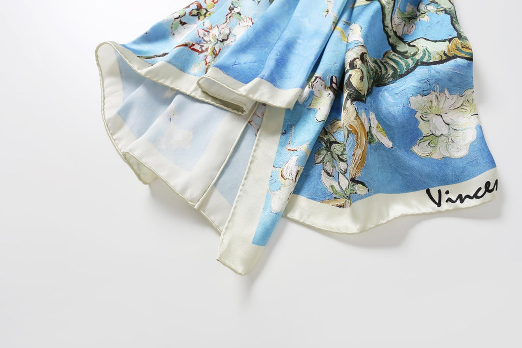 Corner of the almond blossom silk scarf showing the cream border and the painted signature