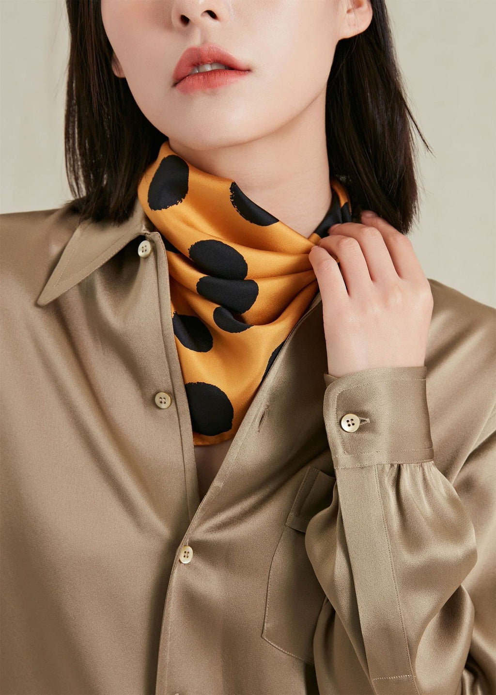 Close view of the golden yellow dotted silk gathered at the throat above a khaki shirt