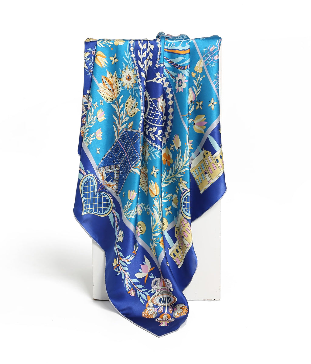 The cobalt folk art silk scarf hanging in long folds showing tulips and cottages